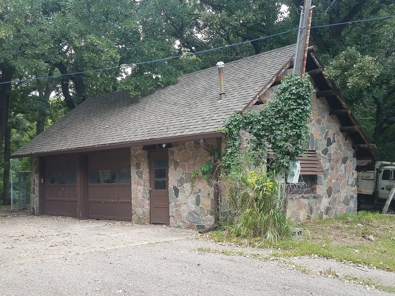 A low rustic stone service building stands in a wooded clearing.