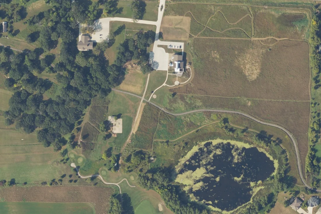 Natural-color aerial photograph of Dickinson County Nature Center and its Kenue Park grounds, showing the building, prairie paths and wetland loop, September 11, 2025.